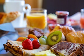 Une table mise pour le petit-déjeuner avec des tartines, des fruits et un verre de jus d’orange.