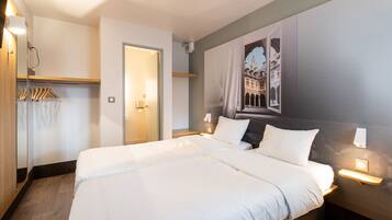 Une chambre d’hôtel avec un grand lit, des lampes de chevet, une armoire et un tableau accroché au mur.