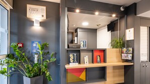 Un área de recepción con mostrador, diplomas enmarcados, una planta en maceta y un letrero en la pared.