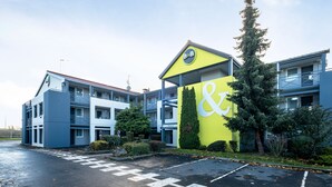 A building with a blue and yellow facade, a large sign with "&" and "B&B" on it, and a parking lot in front.