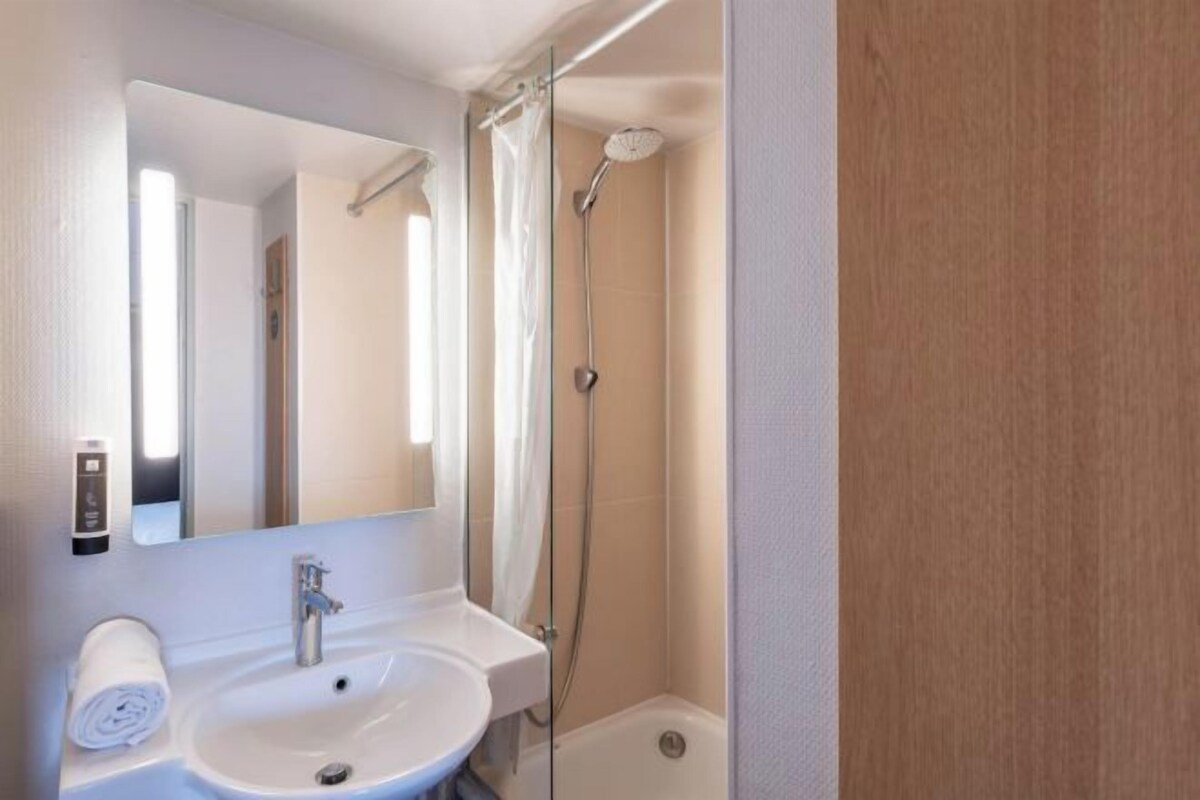 Un baño moderno con lavamanos, espejo y ducha.