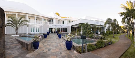 Un hotel con un patio central, varias piscinas y un jardín bien cuidado.