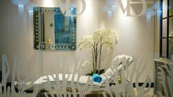A spa room with a massage chair, a mirror, and a vase of white orchids.