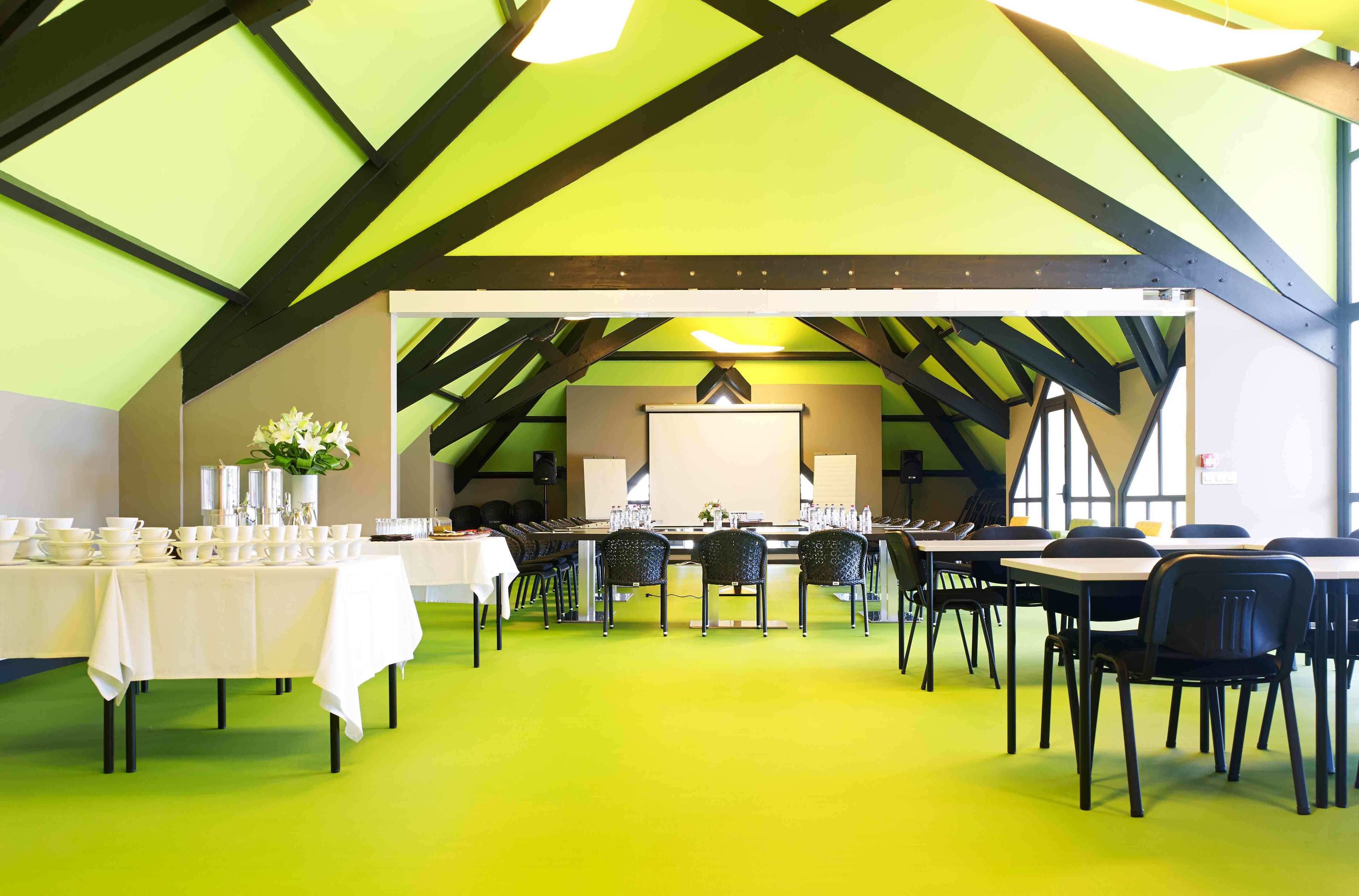 A dining area with tables and chairs, a white tablecloth, and a green floor.