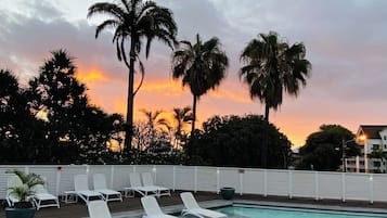 Una piscina al aire libre, sombrillas, tumbonas