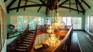 A spacious room with a high ceiling, wooden staircase, and a chandelier. - Villa Delisle Hôtel & Spa (Saint-Pierre)