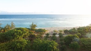 A beach with people and palm trees, viewed from a distance. - Villa Delisle Hôtel & Spa (Saint-Pierre)