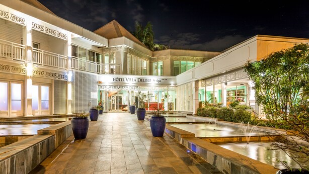 A hotel with a central courtyard featuring fountains, potted plants, and a tiled walkway. - Villa Delisle Hôtel & Spa (Saint-Pierre)