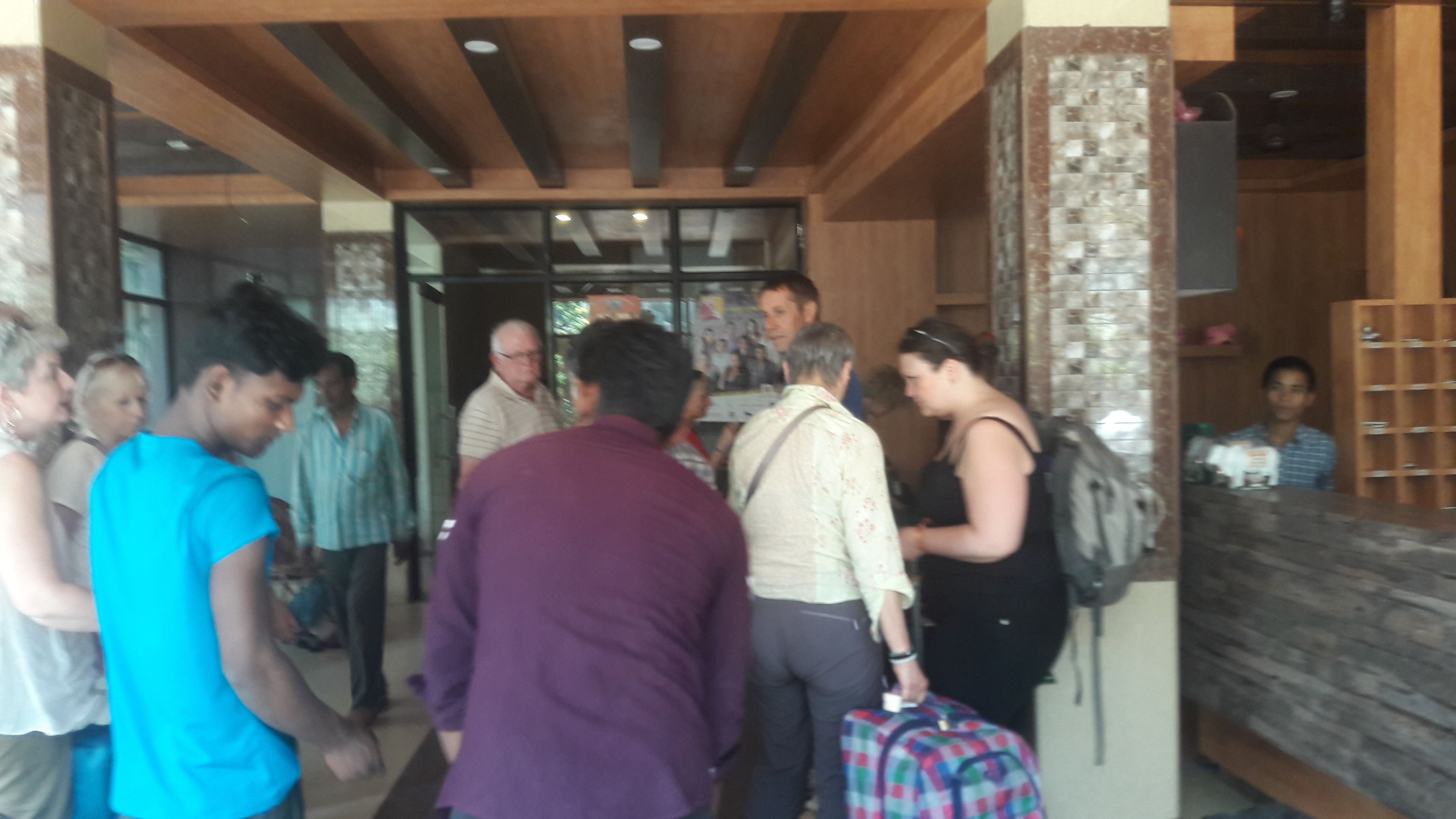 Un grupo de personas entra en un edificio con un interior moderno, que incluye una recepción y una pared de piedra.