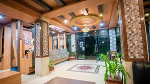 A reception area with a wooden ceiling, a chandelier, a reception desk, and potted plants. - Hotel Welcome (Janakpur)