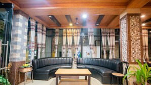 A modern living room with a black leather sofa, a wooden coffee table, and a small side table. - Hotel Welcome (Janakpur)