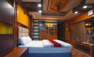 A hotel room with a bed, a desk, a television, and a clock on the wall.