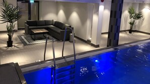 Un área de piscina interior moderna con un sofá modular y plantas en macetas.