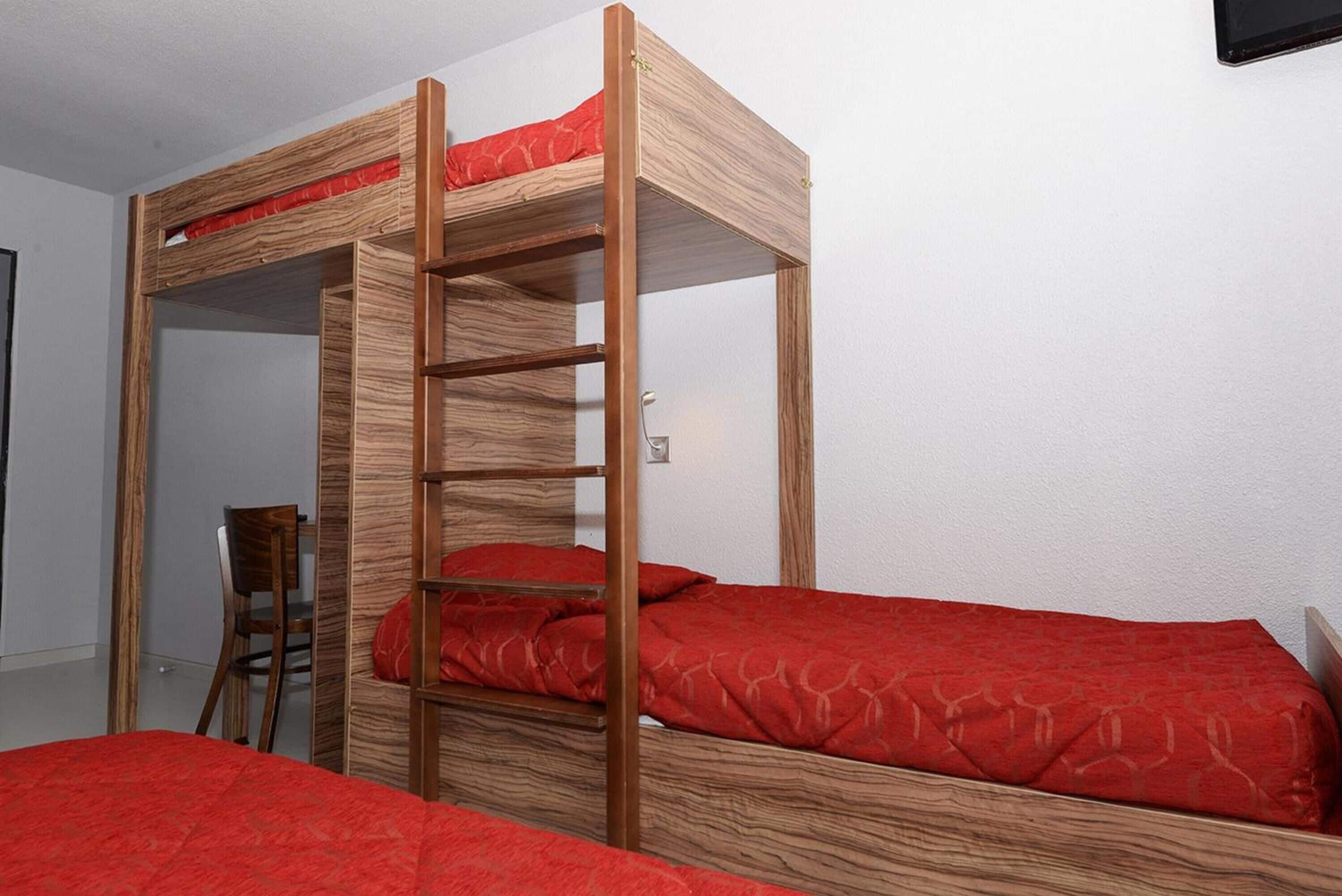 Una cama litera con estructura de madera y ropa de cama roja.