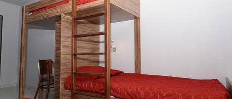 Una cama litera con estructura de madera y ropa de cama roja.