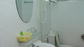 A bathroom with a glass shelf holding toiletries, a toilet, and a shower area. - Venus Hotel (Nha Trang)