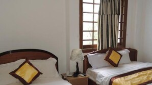 A hotel room with two beds, each with a wooden headboard and white bedding. There is a window with curtains, a bedside table with a lamp, and a telephone. - Venus Hotel (Nha Trang)