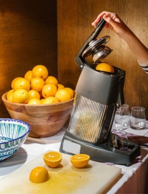 Cozinha com centrífuga, uma tigela de laranjas e tábua de corte com metades de laranja.