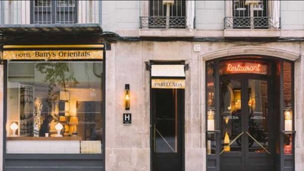 A building with a 'Hotel Bany's Orientals' sign, a 'PARELLOXIA' sign, and a 'Restaurant' sign. - Banys Orientals (Barcelona)