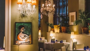A restaurant with tables set for dining, chandeliers, and a painting on the wall. - Banys Orientals (Barcelona)