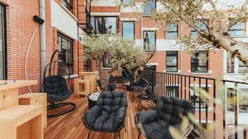 Eine Terrasse im Freien mit Holzboden, schwarzen Sitzgelegenheiten und einem kleinen Tisch.
