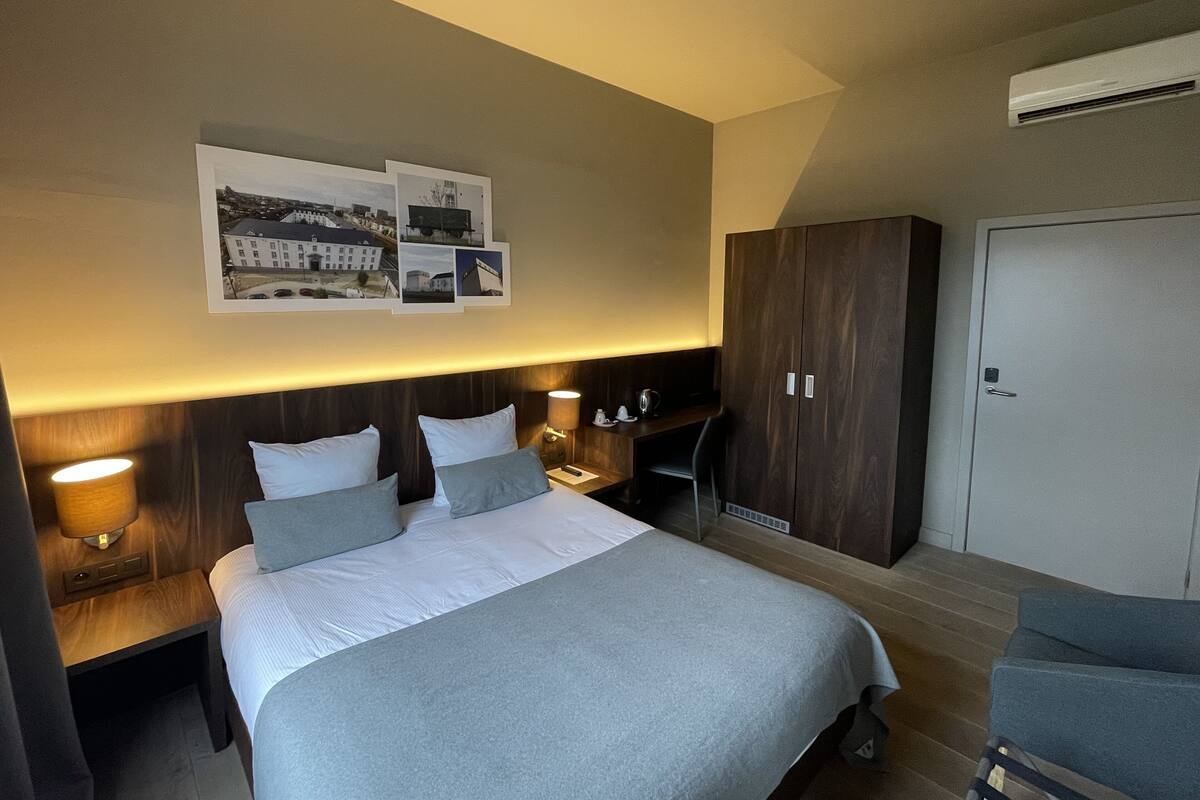 Ein Hotelzimmer mit einem großen Bett, Nachttischen, einem Kleiderschrank und einer Wand-Klimaanlage.