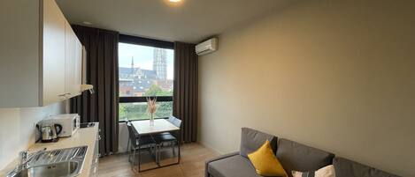 A compact living space with a kitchenette, a dining area, and a sofa.