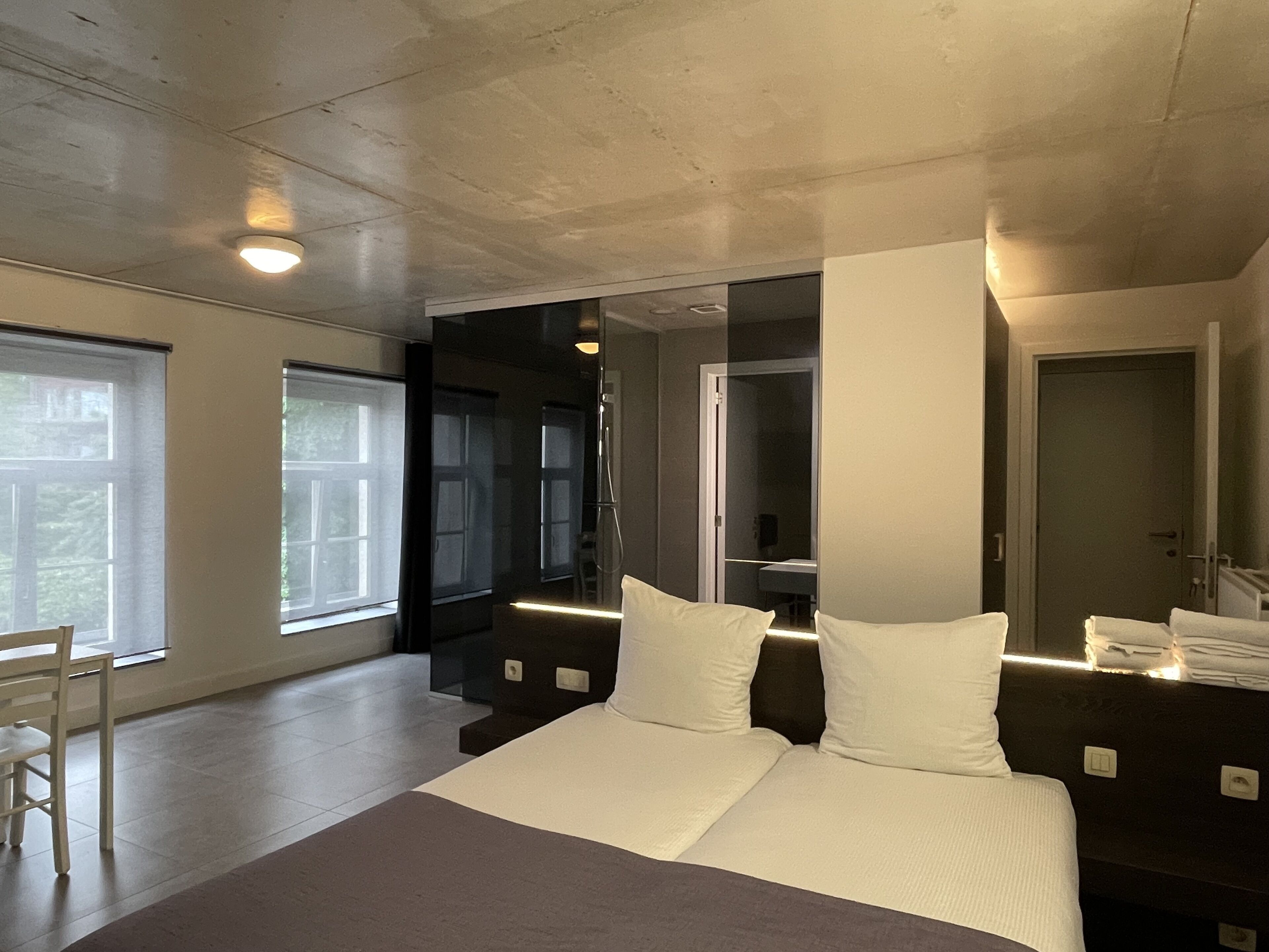 A modern hotel room with a large bed, a seating area, and a view of the outdoors.