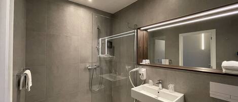 A modern bathroom with a glass shower enclosure, a white sink, and a large mirror.