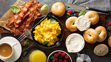 A breakfast setting with bacon, scrambled eggs, bagels, and fresh berries.
