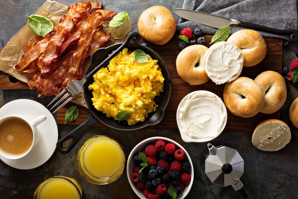 A breakfast setting with bacon, scrambled eggs, bagels, and fresh berries. - Hilton Garden Inn Miami South Beach (Miami Beach)