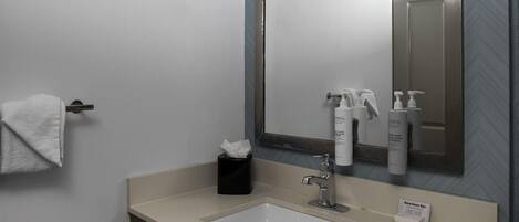 Une salle de bain équipée d’un lavabo, d’un miroir, d’une serviette et d’articles de toilette.
