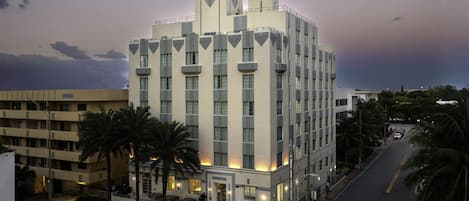 Un hôtel à plusieurs étages doté d’une architecture moderne, avec une tour imposante et une entrée bien éclairée.