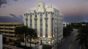 Um hotel de vários andares com design arquitetônico moderno, com varandas e uma torre central.