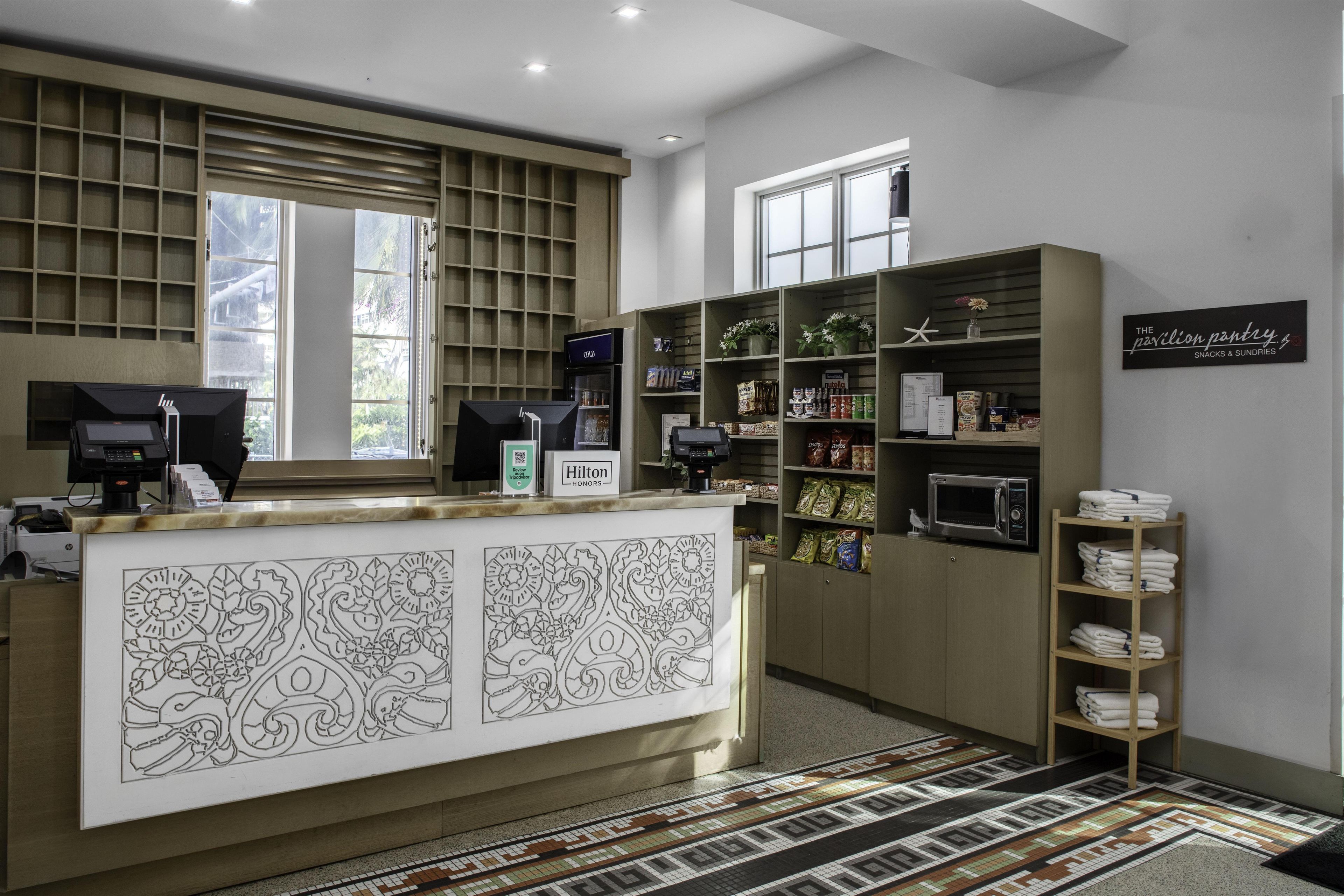 Ein Hotel-Empfangsbereich mit einer Rezeption, Verkaufsautomaten und Regalen voller Snacks und Kleinigkeiten.