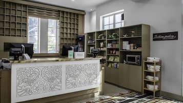 Ein Hotel-Empfangsbereich mit einer Rezeption, Verkaufsautomaten und Regalen voller Snacks und Kleinigkeiten.