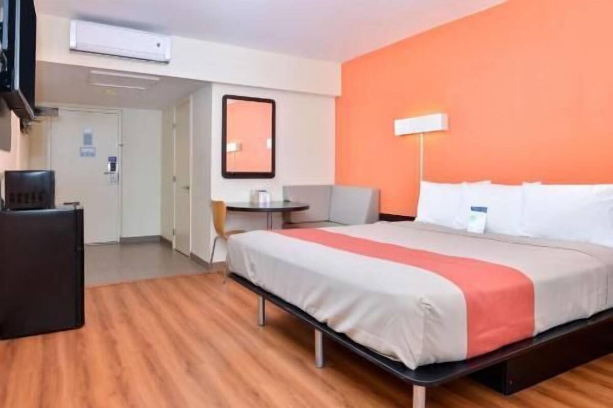 A hotel room with a bed, a desk, a chair, and a small table.
