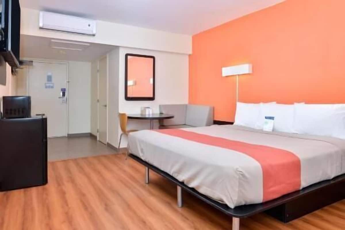 A hotel room with a bed, a desk, a chair, and a small table.