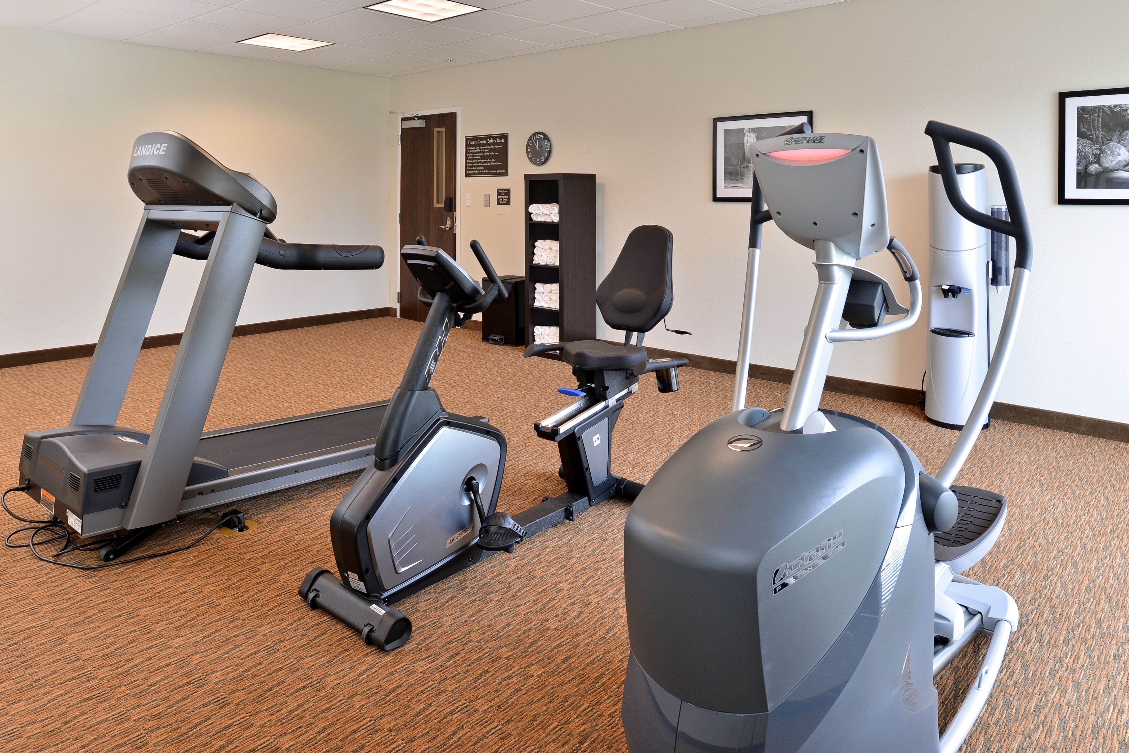 Een fitnessruimte met loopbanden, elliptische trainers en een hometrainer.