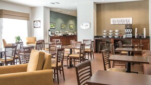 Un vestíbulo de hotel con varias zonas de estar, una recepción y una barra de desayuno.