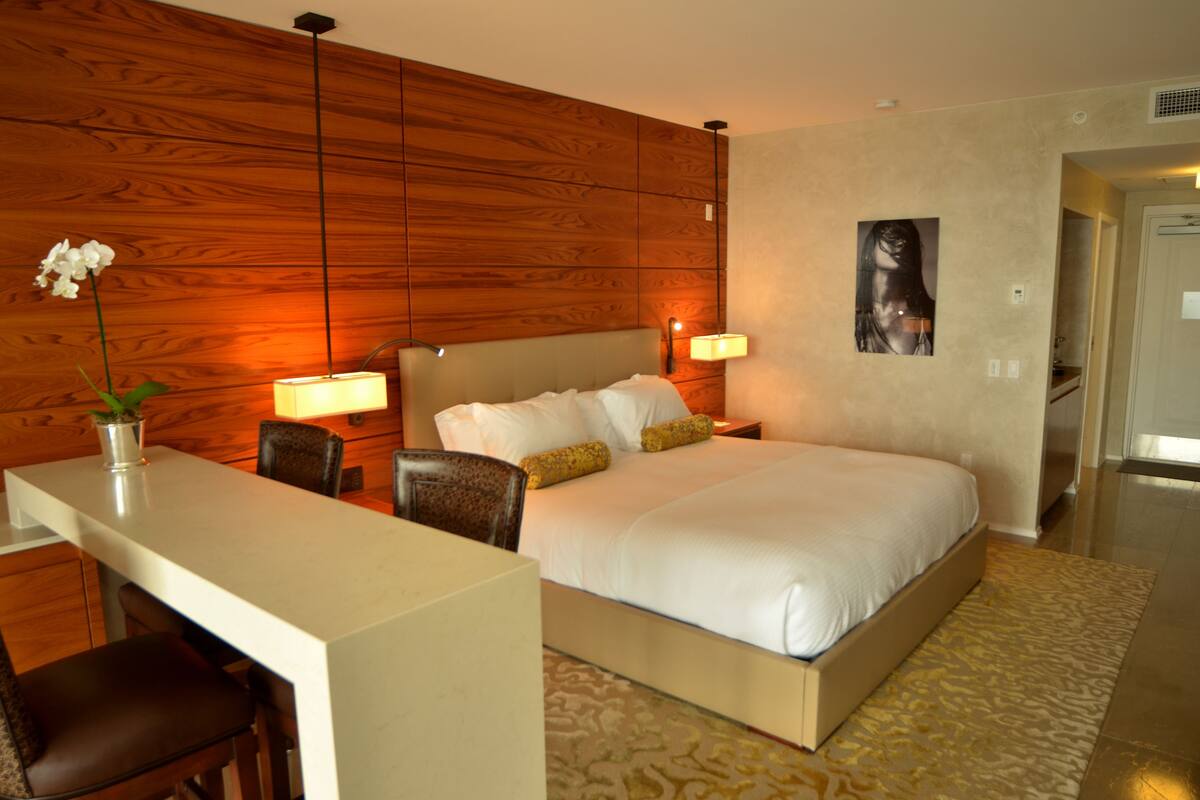 A hotel room with a bed, bedside tables, a desk, and a chair.