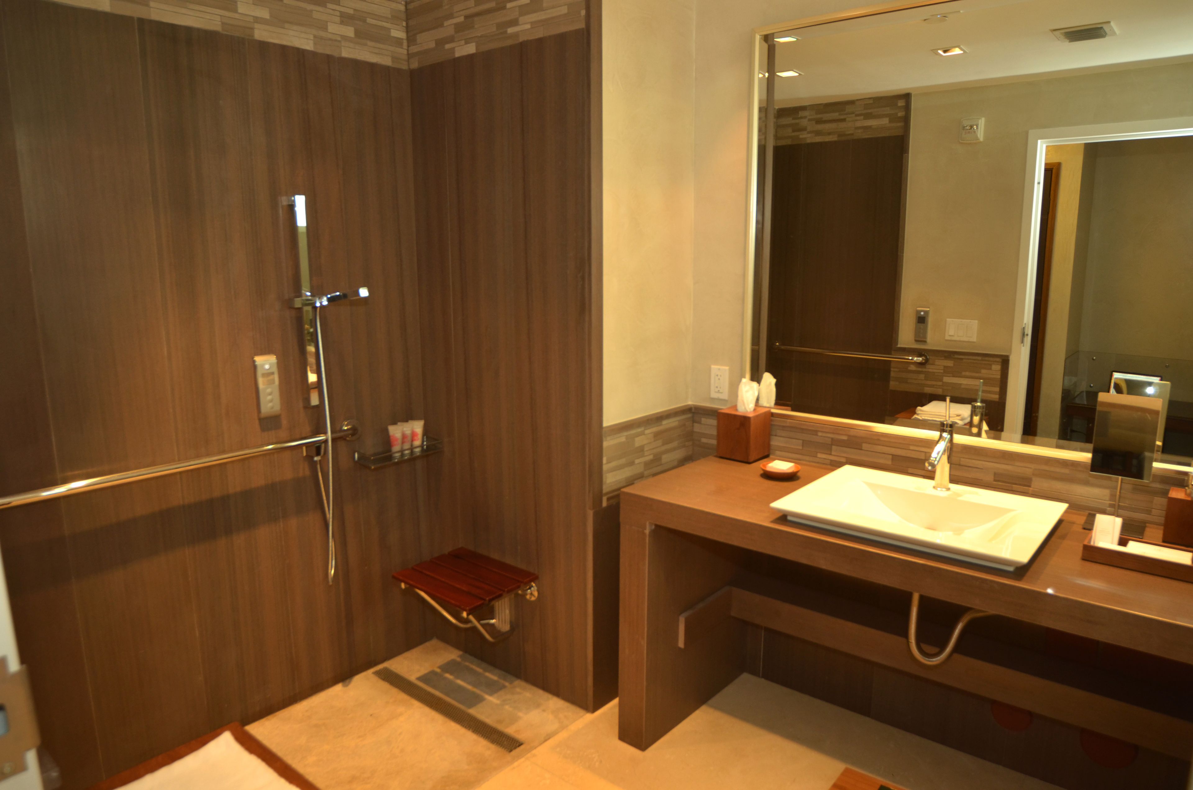 A modern bathroom with a walk-in shower, a vanity with a sink, and a large mirror.