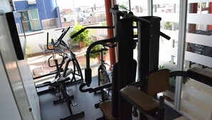 A gym with exercise equipment, a window with a view of buildings, and a door.