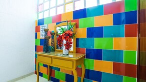 A room with a colorful tiled wall, a wooden table with decorative vases, and a window with a view.