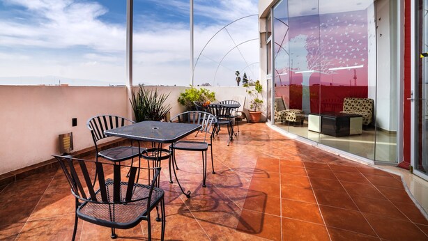 A covered patio with outdoor seating, a glass door entrance, and a view of the sky.