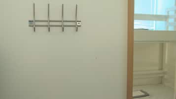 Una pared blanca con un perchero metálico.