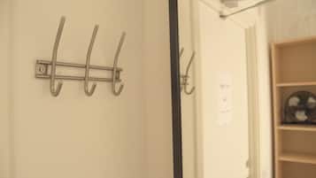 A wall-mounted metal hook system with a door frame and a wooden shelf with a fan.