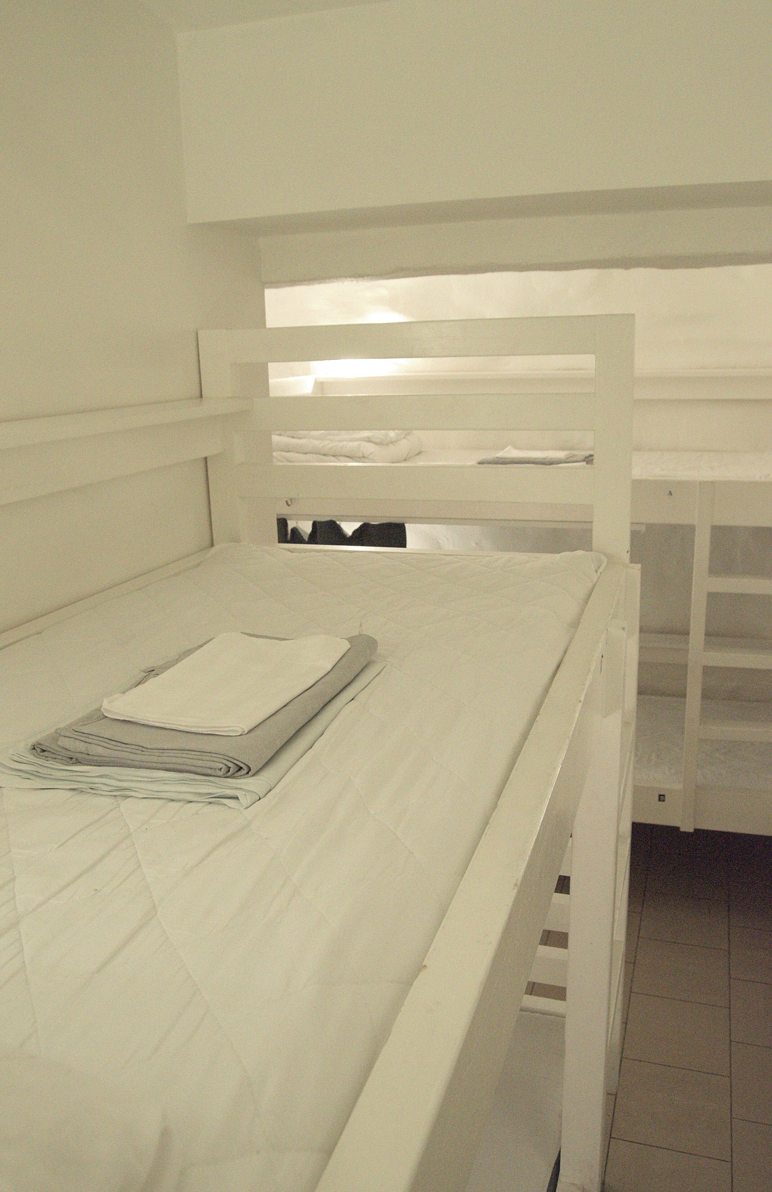 A bunk bed with a neatly folded blanket and a rolled-up towel on the lower bunk.