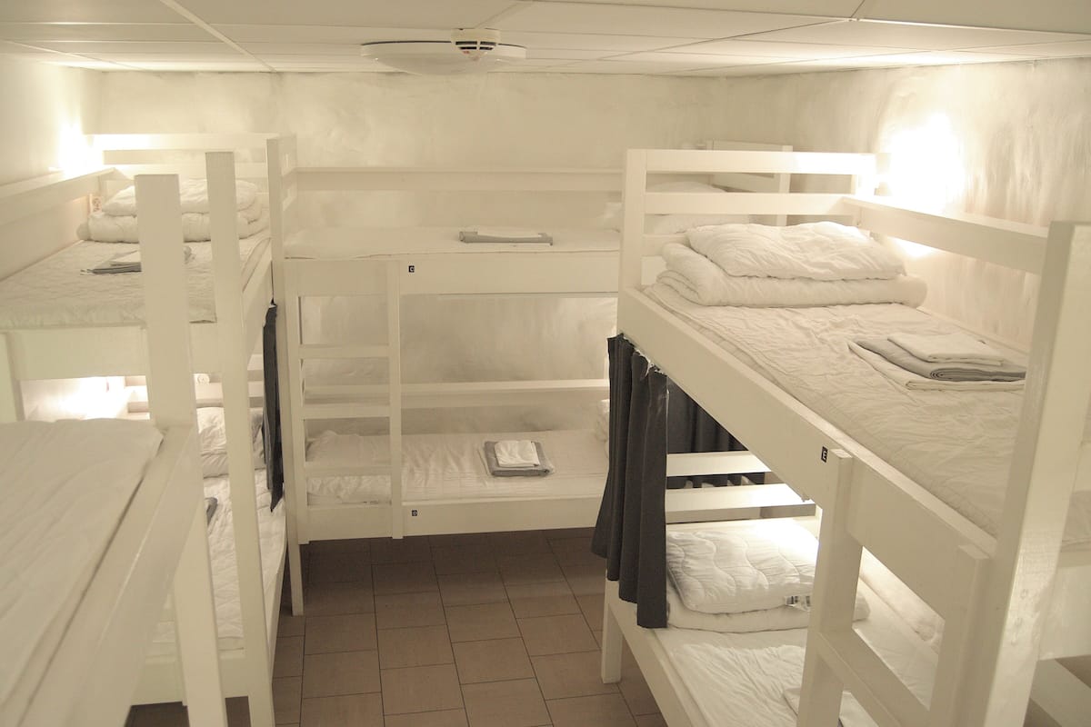 Asuntolan huone, jossa on kerrossängyt, laattalattia ja kattotuuletin.