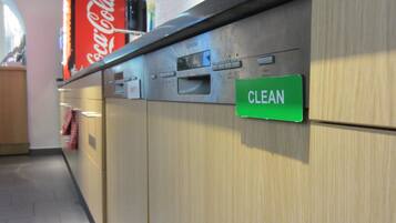 Una cocina con lavavajillas, un cartel de Coca-Cola y un letrero que dice 'LIMPIO'.